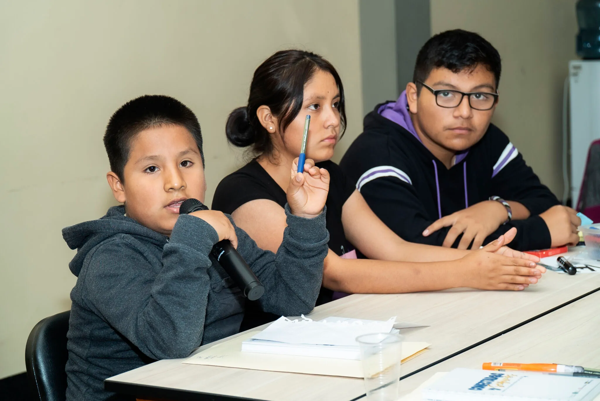 Un niño habla ante un micrófono, acompañado de otras y otros adolescentes, en una actividad por los derechos de la niñez.