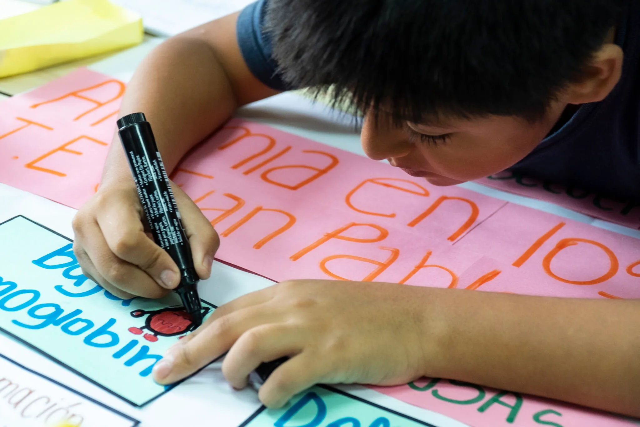 Un niño escribe sobre un papelógrafo durante una actividad de análisis por los derechos de la niñez.