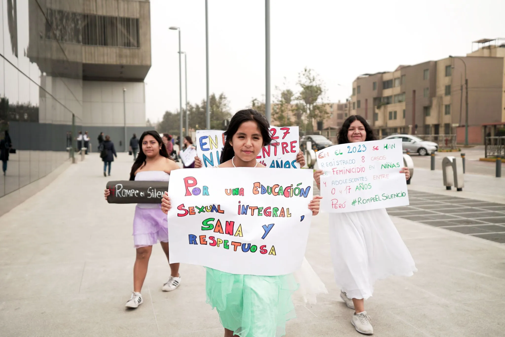 Tres adolescentes marchan con carteles hechos a mano por una educación sexual integral y contra la violencia hacia la niñez.